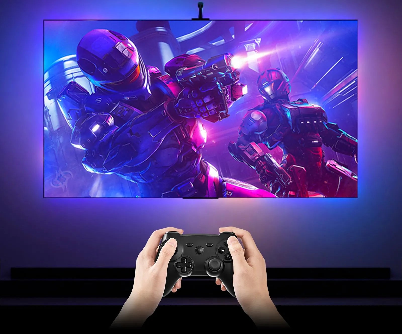 Hands on a controller in front of a lit TV, blue and pink light across the wall